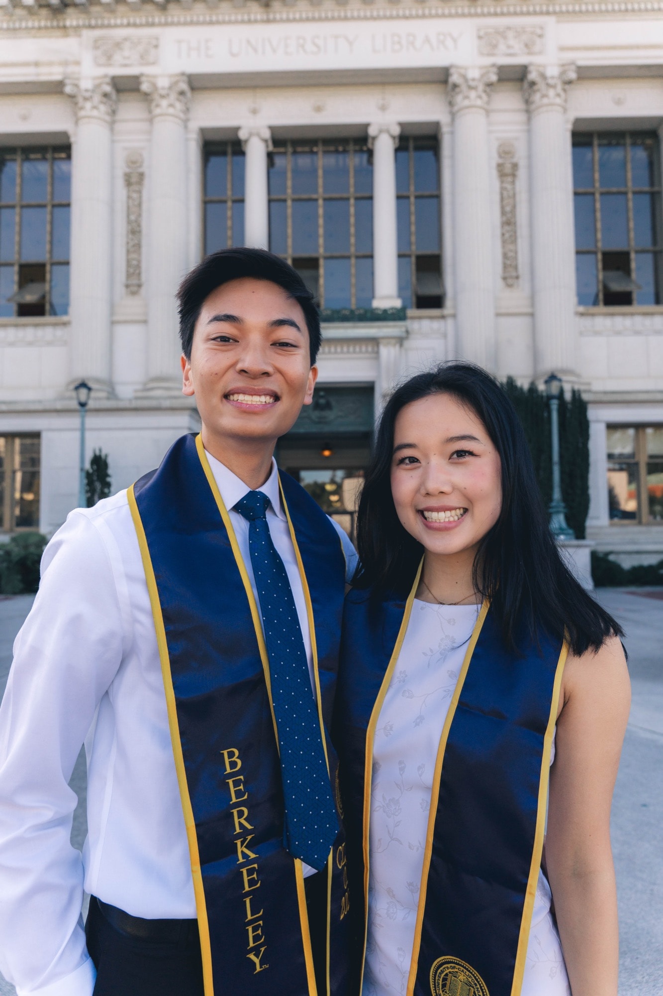Two graduates side by side, library facade behind